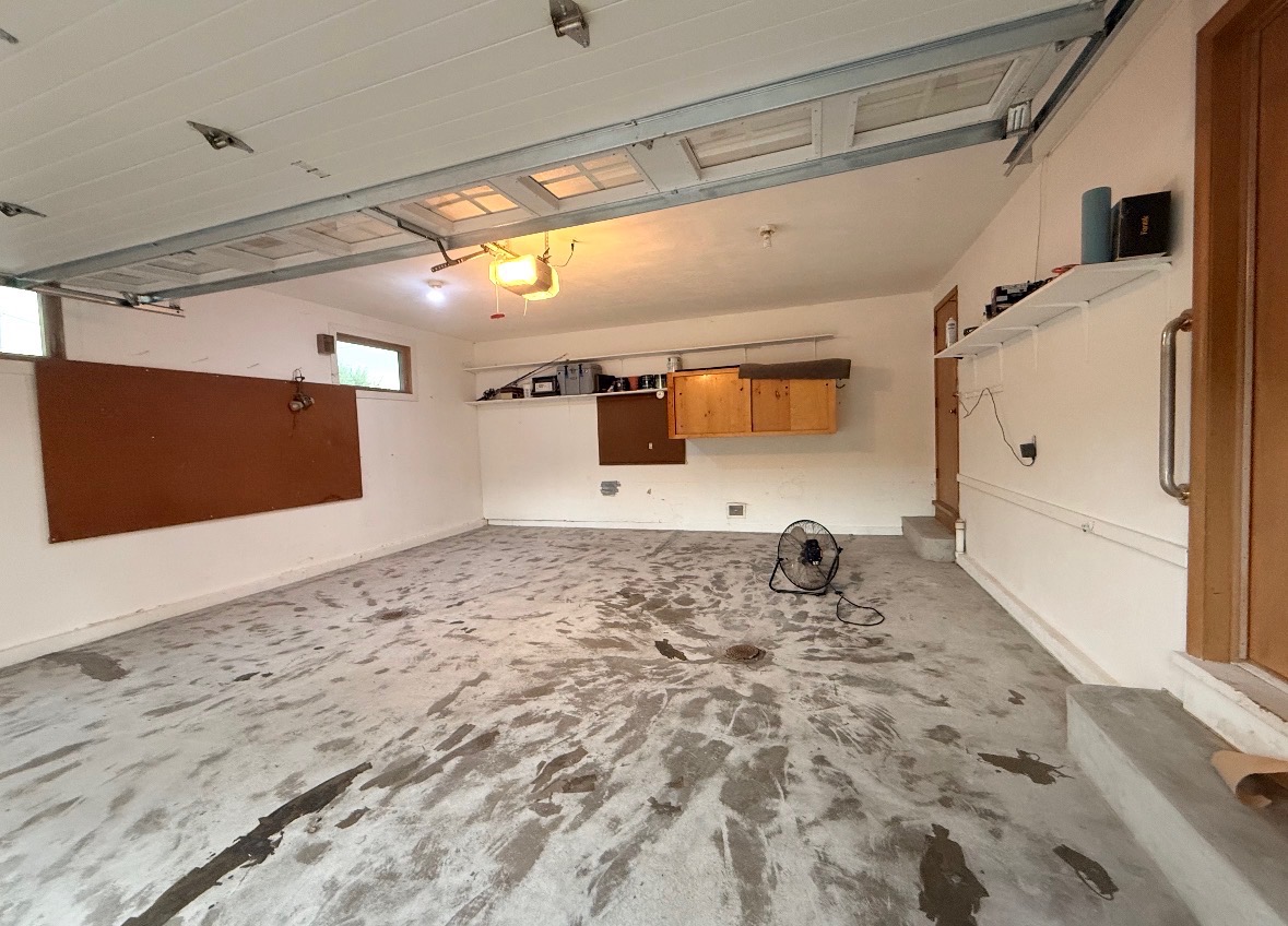 Omaha garage with stained, worn bare concrete floor before coating