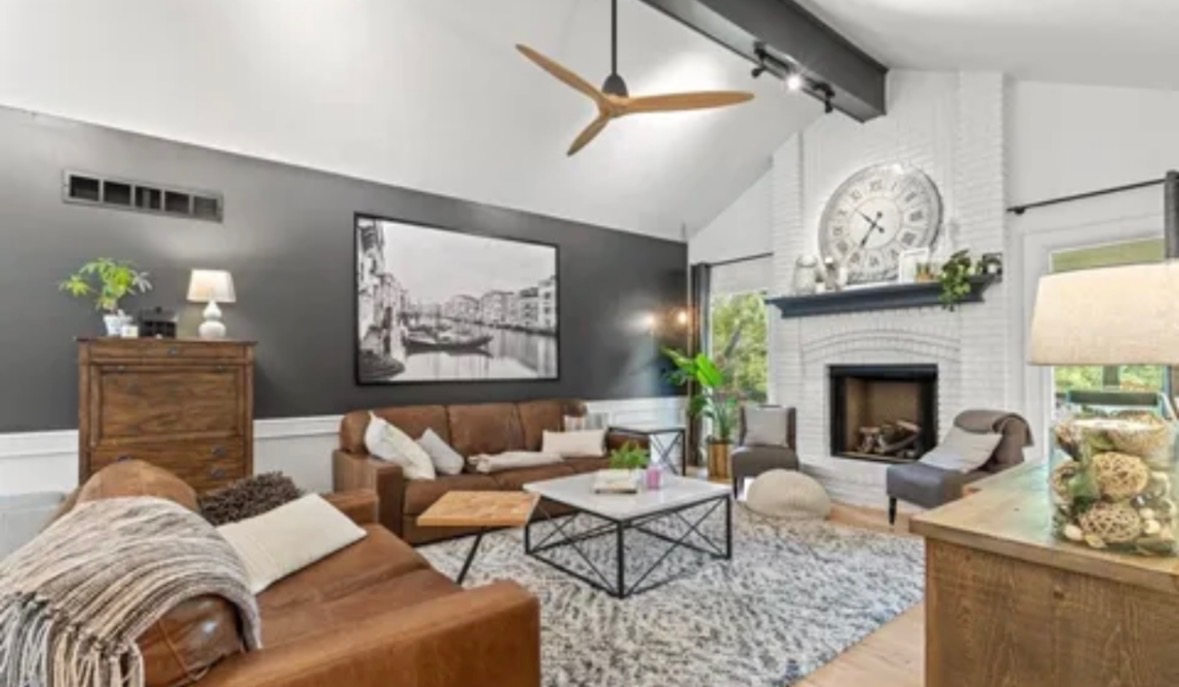 Modern Omaha living room with a charcoal gray accent wall, white painted fireplace, and brown leather seating